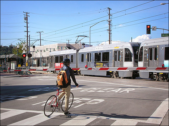 A cyclist waits for a Gold Line train to pass in South Pasadena